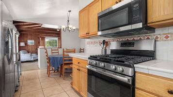 Una cocina con muebles de madera, estufa de acero inoxidable y microondas.