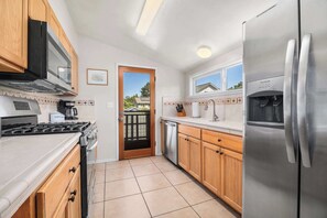 Een moderne keuken met roestvrijstalen apparatuur, houten kastjes en een betegelde vloer.