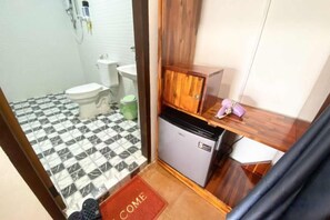 A compact bathroom with a toilet, sink, and a small refrigerator. - Villay Vanh Place House (Luang Prabang)