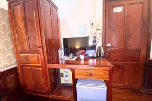 A wooden desk with a small refrigerator, a television, and a few personal items.