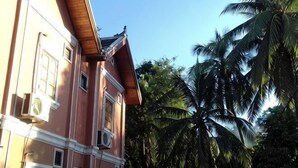 Um edifício com várias andares e varandas, rodeado por palmeiras.