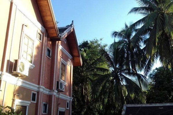A multi-story building with balconies, surrounded by palm trees.
