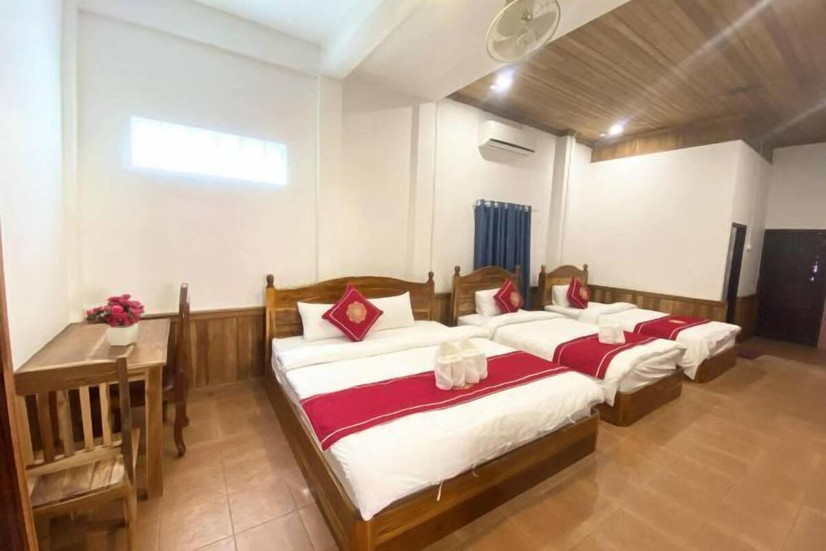 A hotel room with a large bed, a bedside table with a vase of flowers, and a ceiling fan.