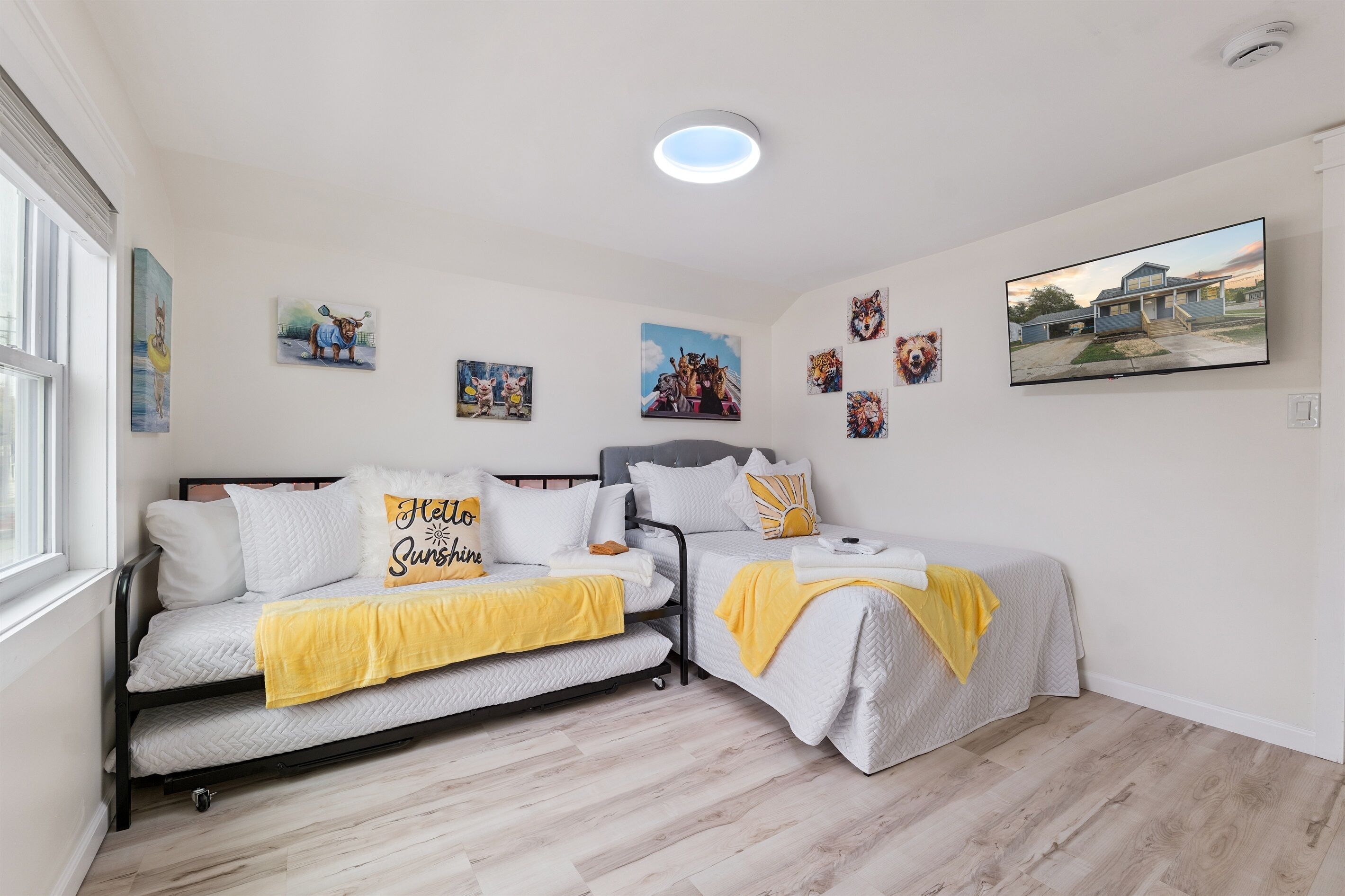 Quarto com duas camas, uma janela grande e várias obras de arte nas paredes.