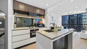 A modern kitchen with a central island, built-in appliances, and a large window providing natural light.