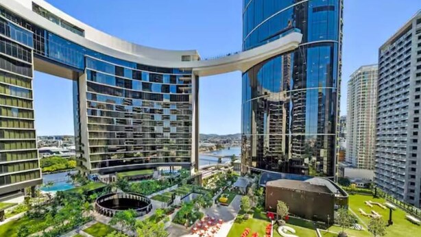 A modern hotel complex with multiple high-rise buildings, a central courtyard with greenery, and a large pool area.