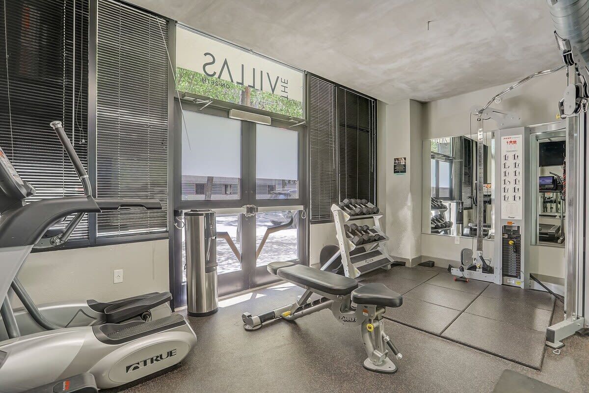 A gym with treadmills, weight machines, and dumbbells.