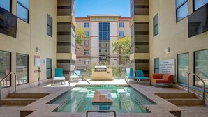 A pool area with a lifeguard on duty sign, lounge chairs, and a building in the background.