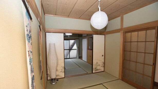 Ein traditioneller japanischer Raum mit Tatami-Böden, Shoji-Schirmen und einer hängenden Papierlaterne.