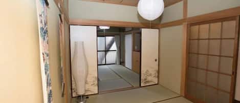 Una habitación japonesa tradicional con suelo de tatami, paneles shoji y un farol de papel colgante.