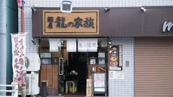 A storefront with a sign in Japanese, a closed shutter door, and a small display window.