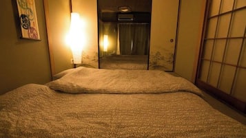 A hotel room with a bed, a wall-mounted lamp, and a sliding door leading to a bathroom.