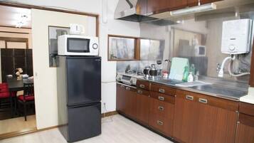 A compact kitchen with a microwave, refrigerator, and wooden cabinets.
