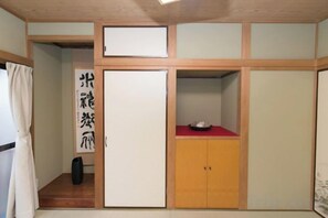 A room with a sliding door, a cabinet with a red top, and a large whiteboard with Japanese characters. - Nishioi House (Tokyo)