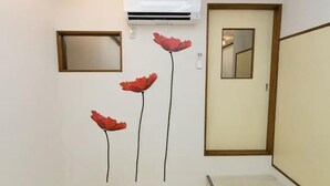 Ein Flur mit weißer Wand, einer Tür mit Spiegel und einer Wand-Klimaanlage.
