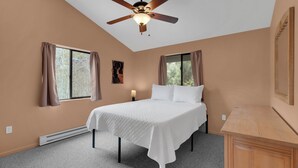 Quarto com cama, ventilador de teto, janelas e mesa de cabeceira.