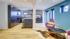 A modern kitchen with grey cabinets, a central island, and a dining area with a cowhide rug and a small table. - Very spacious apt with ground level easy access in Morzine center (MORZINE)