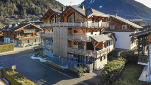 A multi-story wooden building with balconies, set against a mountainous backdrop. - Very spacious apt with ground level easy access in Morzine center (MORZINE)