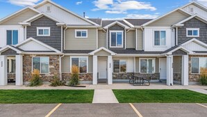 Une rangée de maisons de ville avec des éléments décoratifs en pierre, un patio central et un parking.