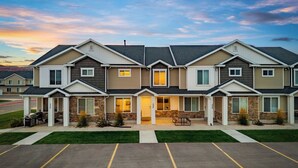 Une rangée de maisons de ville modernes à deux étages, dotées d’une entrée centrale, d’un patio couvert et d’un parking.