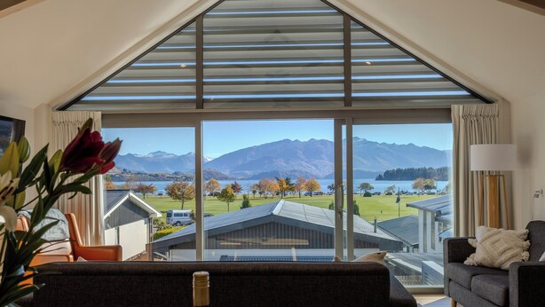 Ein modernes Wohnzimmer mit einem großen Fenster, das einen Blick auf Berge und einen See bietet.