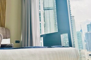 A hotel room with a bed, a window, and a view of tall buildings. - Star Residence KLCC By Starlight (Kuala Lumpur)