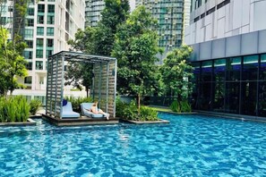 Ein Poolbereich mit einer schwimmenden Liege und einem Glasgebäude im Hintergrund.