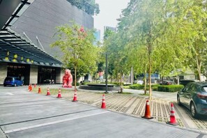 A building entrance with a red statue, a blue car, and orange traffic cones. - Star Residence KLCC By Starlight (Kuala Lumpur)