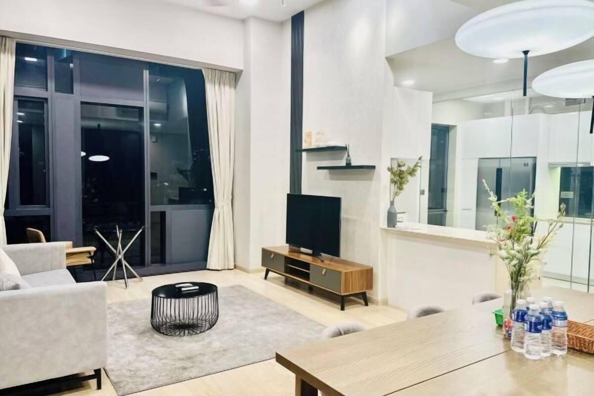A modern living room with a sofa, a coffee table, a TV, and a dining table with water bottles.