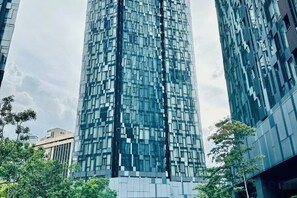 A tall, modern glass building with a grid-like facade, surrounded by trees and other buildings. - Star Residence KLCC By Starlight (Kuala Lumpur)