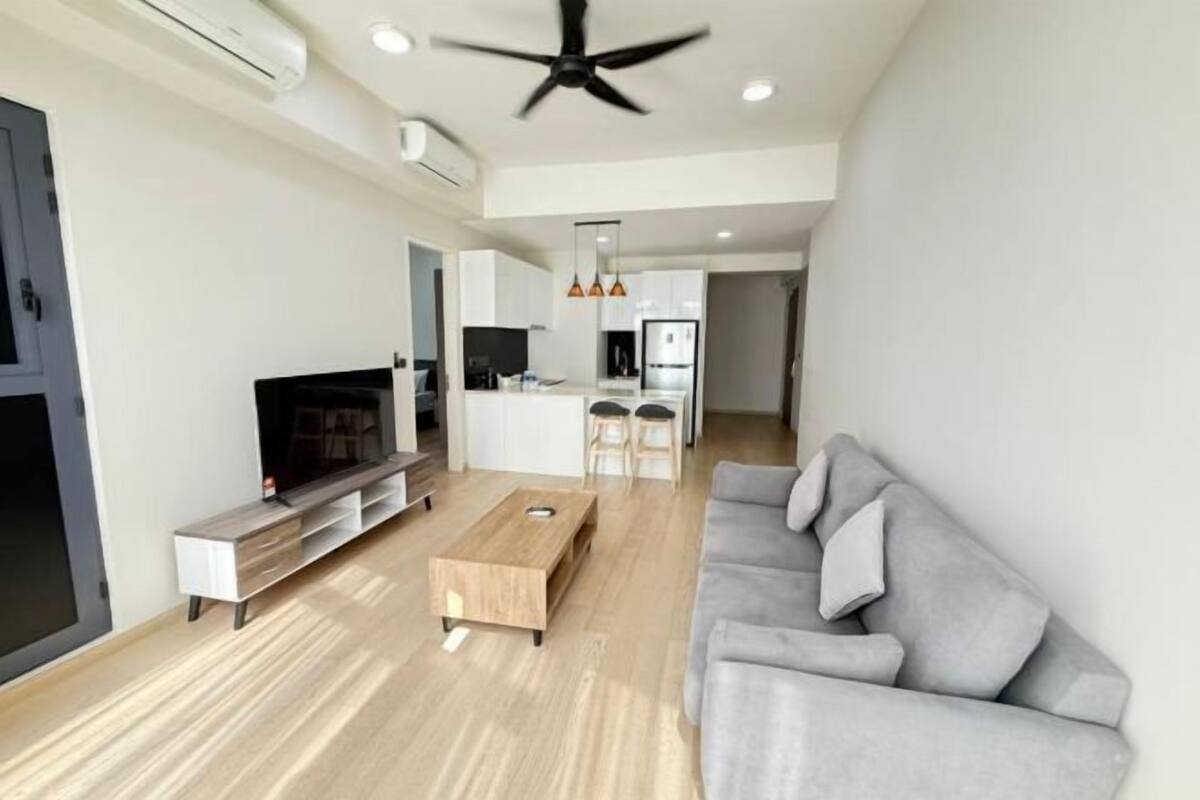 A modern living room with a flat-screen TV, a wooden coffee table, and a grey sofa.