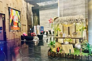 A hotel lobby with a reception desk, seating area, and a decorative plant arrangement. - Star Residence KLCC By Starlight (Kuala Lumpur)
