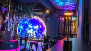 A restaurant with a large illuminated globe, modern furniture, and a neon sign.
