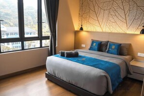 Ett hotellrum med en stor säng, utsikt genom ett fönster och en dekorativ vägg.