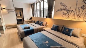 A hotel room with two beds, a small seating area, a window with curtains, and a wall with a floral design. - Hotel Brynton at Cameron Centrum Mall (Brinchang)