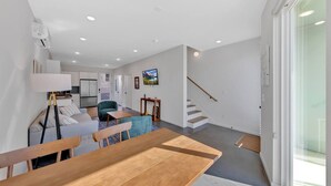 Un interior moderno con comedor, sofá y escalera.