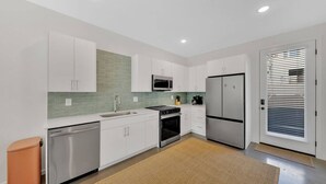 Una cocina moderna con armarios blancos, un refrigerador de acero inoxidable, un microondas y un lavavajillas.