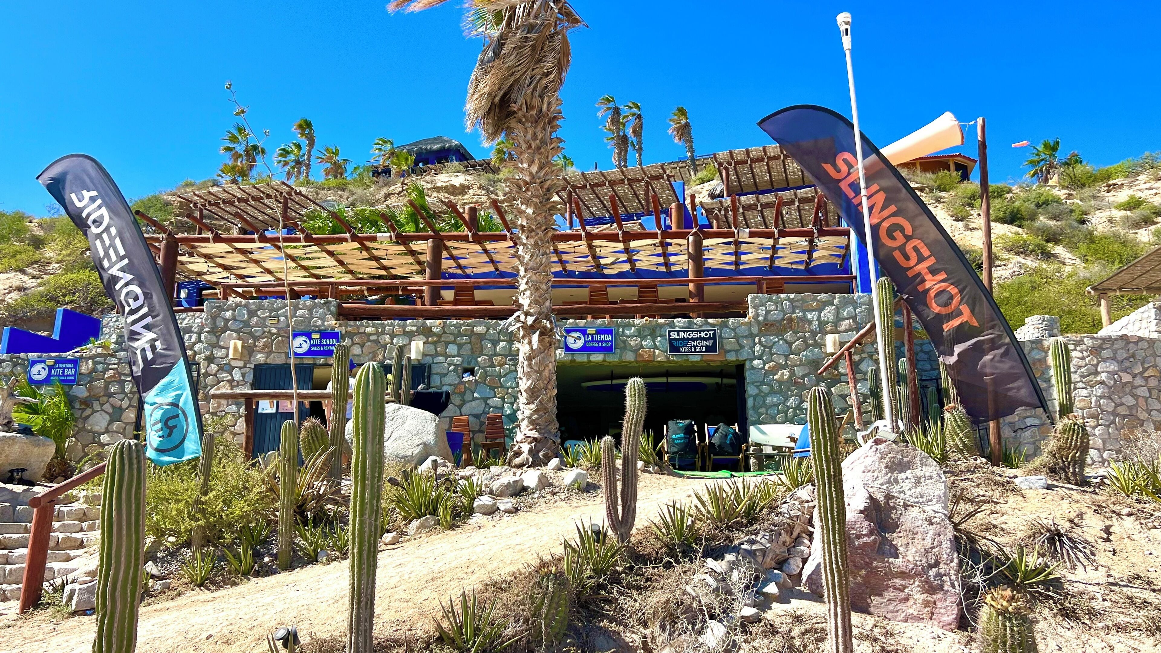 A desert-themed building with a stone facade, a thatched roof, and multiple flags.