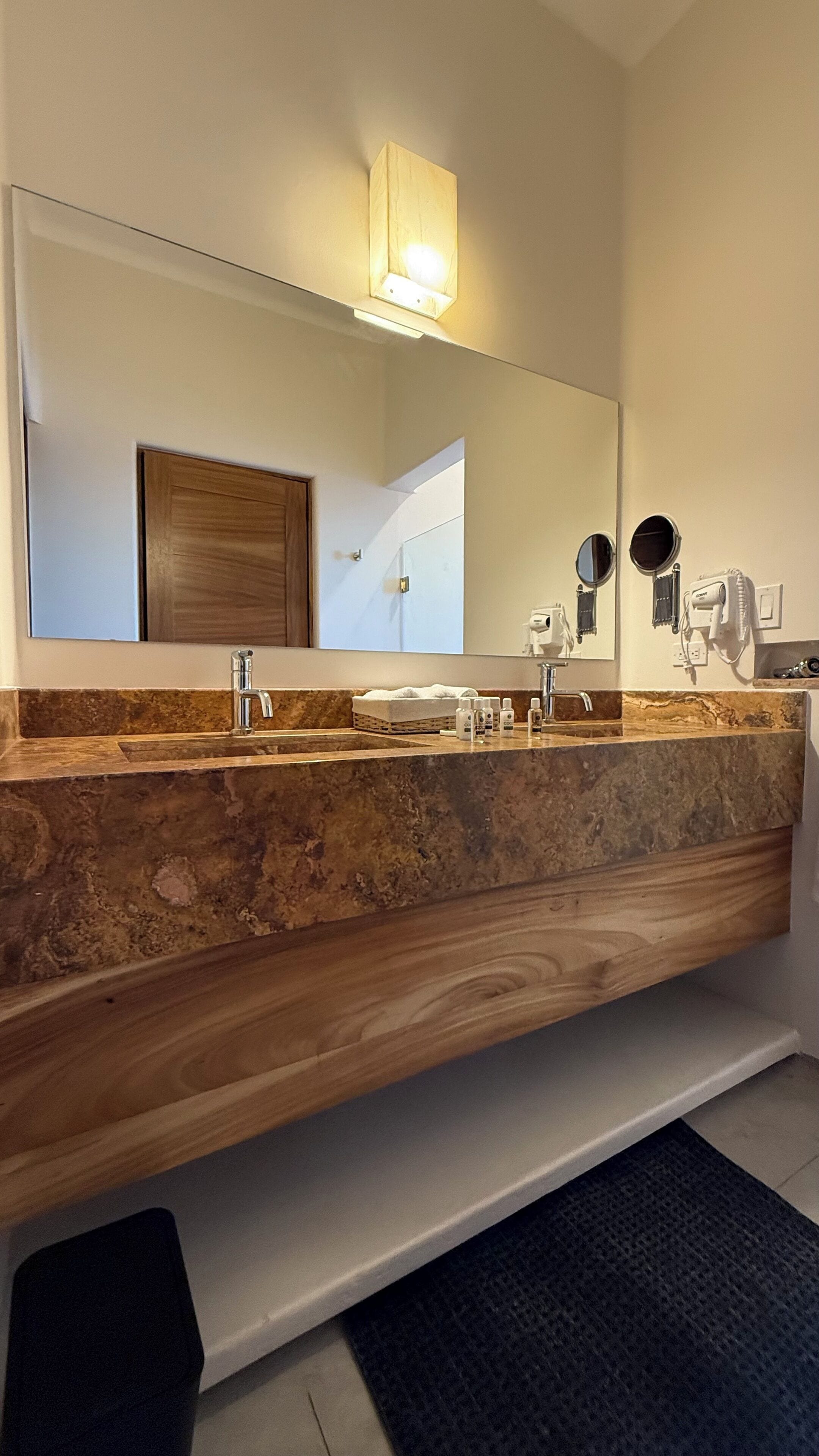 Ein Badezimmer mit Marmorplatte, zwei Waschbecken, einem großen Spiegel und einem Handtuchhalter.