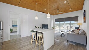 Een moderne keuken met een centraal eiland, houten vloer en hanglampen.