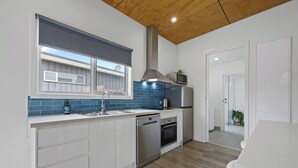 Een moderne keuken met witte kastjes, een blauwe achterwand en een houten plafond.