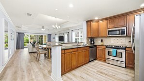 Une cuisine moderne avec des meubles en bois, des appareils électroménagers en acier inoxydable et un grand îlot central.