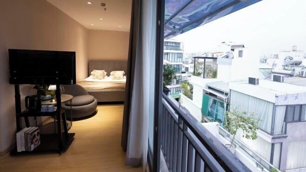 Een moderne kamer met een bed, een tv op een standaard, een klein tafeltje en uitzicht op gebouwen.