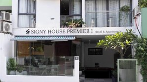 Een hotelentree met een bord waarop staat 'SIGNY HOUSE PREMIER 1 Hotel & Apartments'.