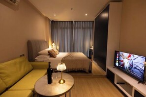 A hotel room with a bed, a television, a sofa, and a table with a lamp. - Signy House Premier 1 (Ho Chi Minh City)