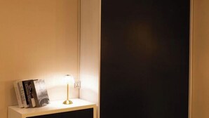 Een nachtkastje met een lamp, een boek en een stopcontact.