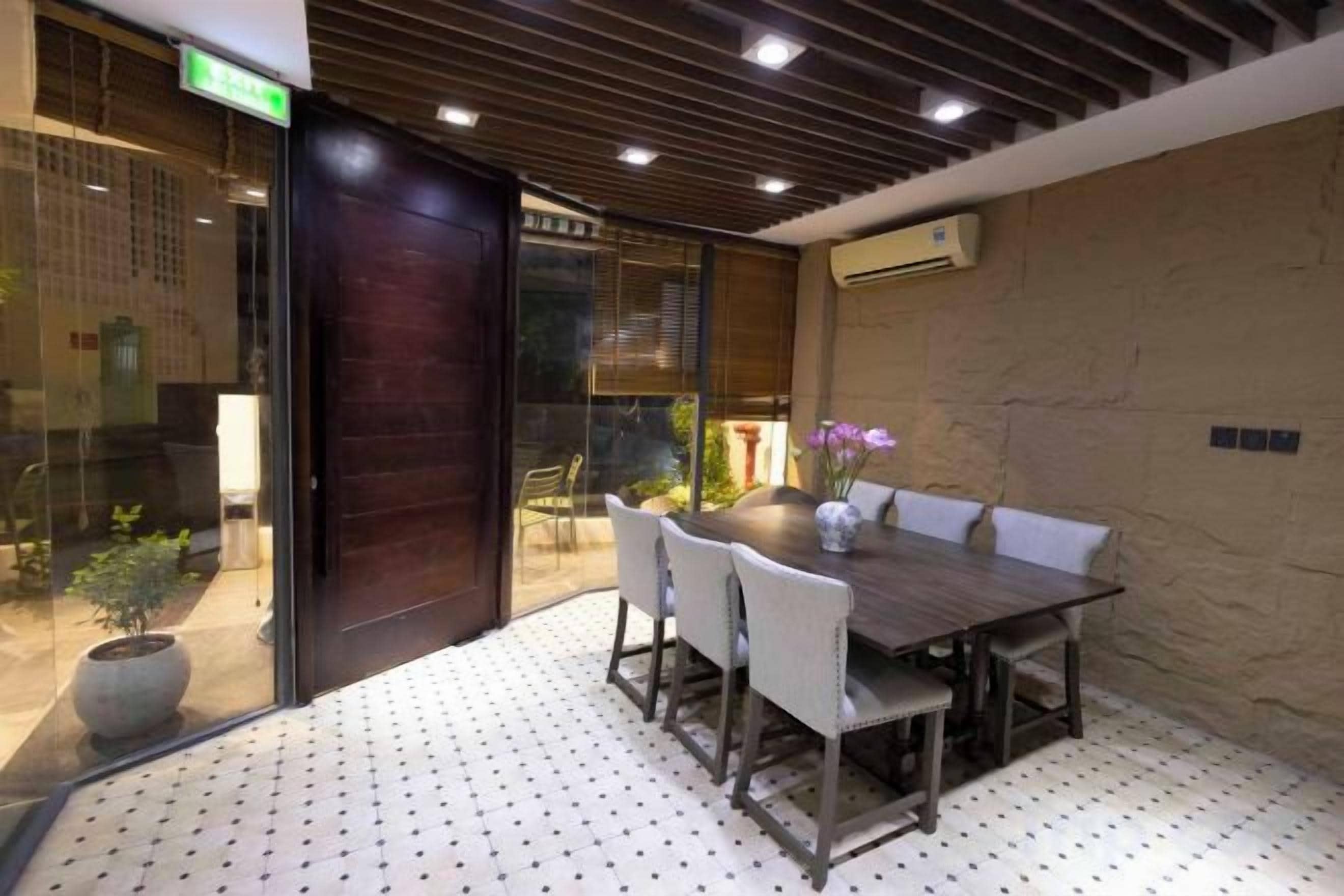 Sala de conferências com uma mesa de madeira, cadeiras brancas e uma planta em vaso.