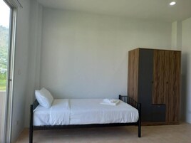 A single bed with white bedding in a room with a wooden wardrobe and a window.