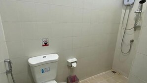 A small, clean bathroom with a toilet, a hand dryer, and a showerhead. - L&P Guesthouse (Karon)