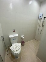 Un baño pequeño y limpio con inodoro, secador de manos y cabezal de ducha.